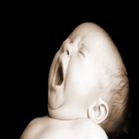 малыш с большой головой зевает